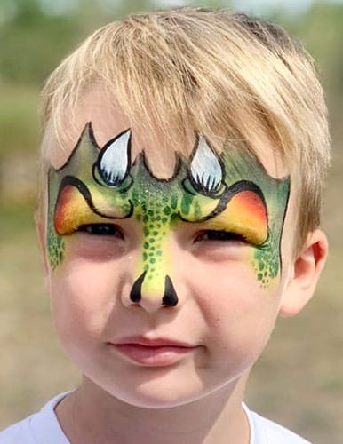 Enfant avec un visage peint en dinosaure